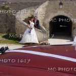 couple mariés en fond escalier en pierre avec devant voiture rouge