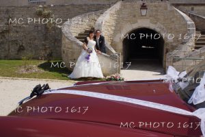 couple mariés en fond escalier en pierre avec devant voiture rouge