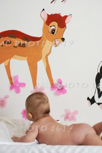 nourisson sur table à langer sans couche avec un mur peint avec bambi charente